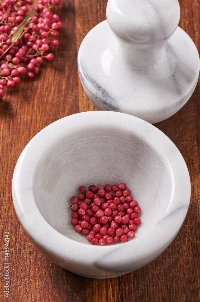 Dry rose pepper in white marble mortar next pestle Dry rose pepper in white marble mortar next pestle