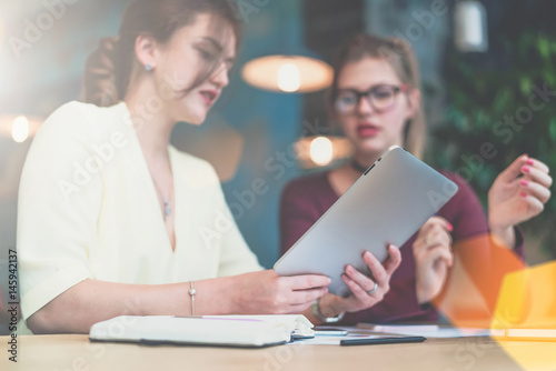 Close-up of tablet computer in hands of young businesswoman sitting at table.