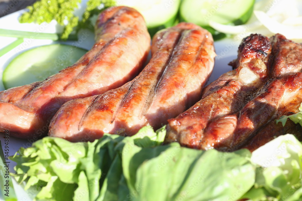 A plate of grilled meat and vegetables lies on the grass. Image with depth of field.