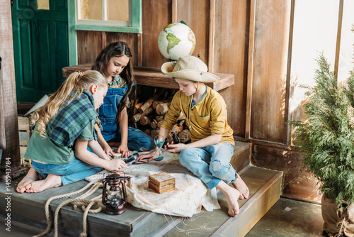 cute kids playing treasure hunt with map on porch