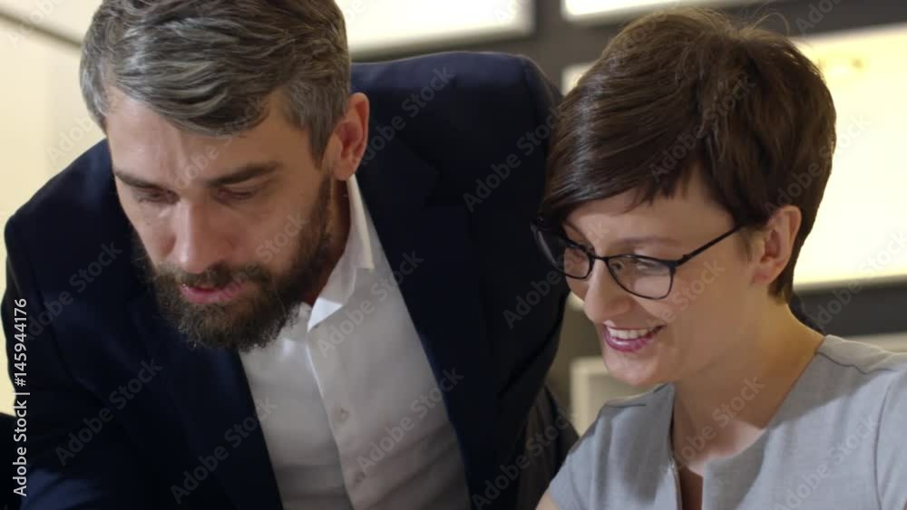 Slow motion of smiling businessman and woman sitting at office table and speaking with director while working together on documents Slow motion of smiling businessman and woman sitting at office table and speaking with director while working together on documents
