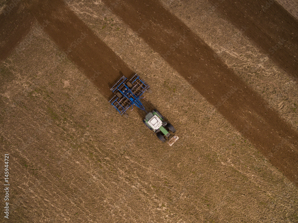 aerial view of a tractor at work - tractor plough cultivating beautiful fields  - agricultural machinery