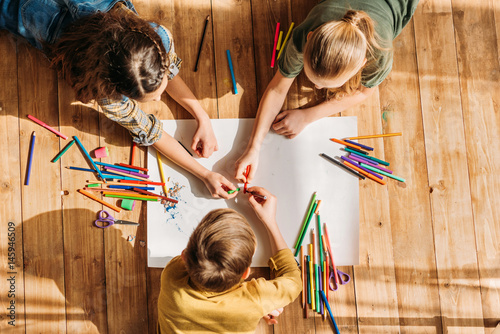 cute kids drawing on paper with pencils while lying on floor photo