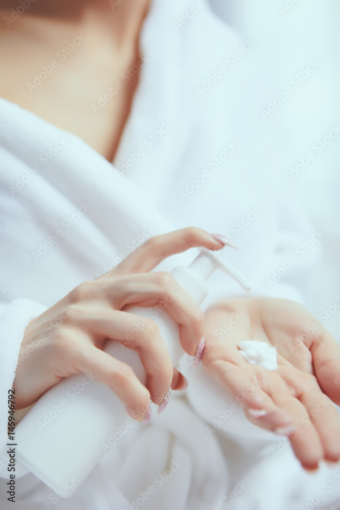 Cropped image of beautiful young woman applying hand cream while sitting on bed at ho Cropped image of beautiful young woman applying hand cream while sitting on bed at ho