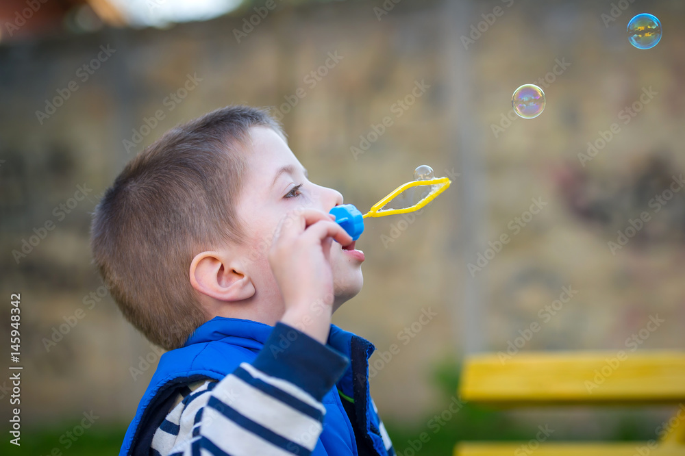 boy blowing bubbles in a little park boy blowing bubbles in a little park