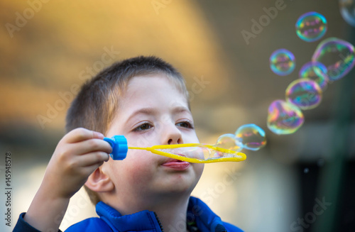 boy blowing soap bubbles in a little park
