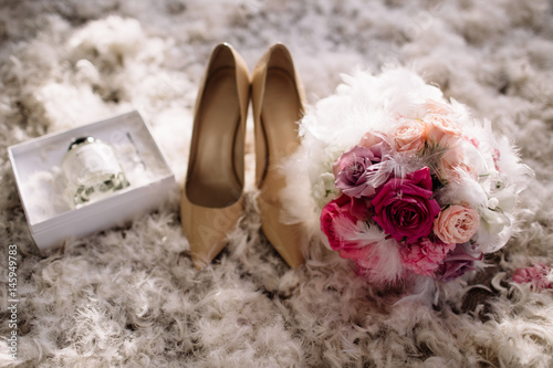 Beautiful set of women's wedding accessories. Bride's morning. White shoes, perfume, pearl necklace and earrings on white lace cloth and sackcloth, canvas. photo