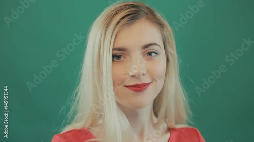 Happy Playful Blond Girl with Long Hair and Sensual Red Lips Posing on Green Background. Portrait of Cute Young Woman Grimacing in Studio.