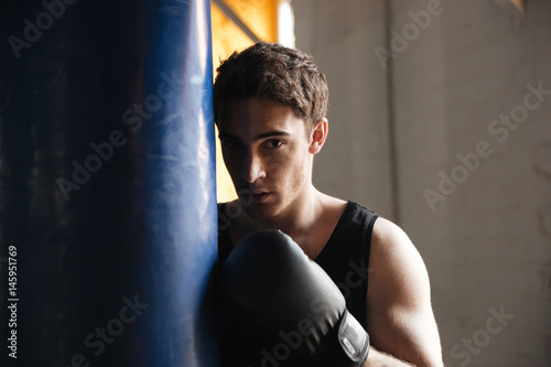 Portrait of boxer near punchbag in shadow