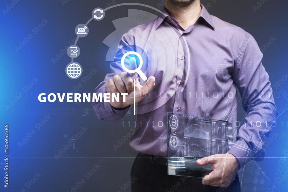 Business, Technology, Internet and network concept. Young businessman working on a virtual screen of the future and sees the inscription: Government Business, Technology, Internet and network concept. Young businessman working on a virtual screen of the future and sees the inscription: Government