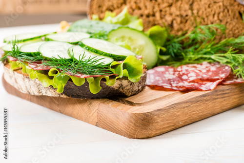 Bread and a sandwich with salami and fresh cucumber