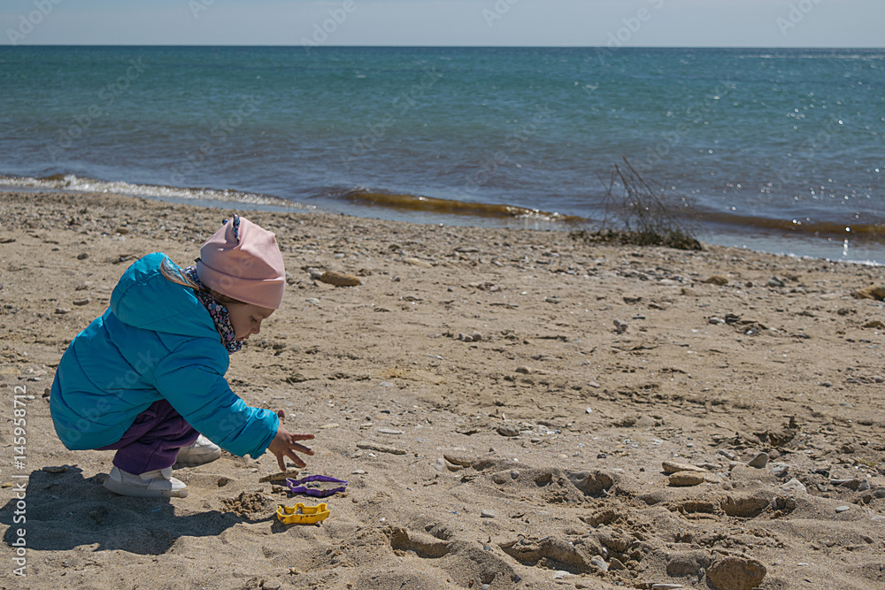 Little white girl playing with sand on the beach Little white girl playing with sand on the beach