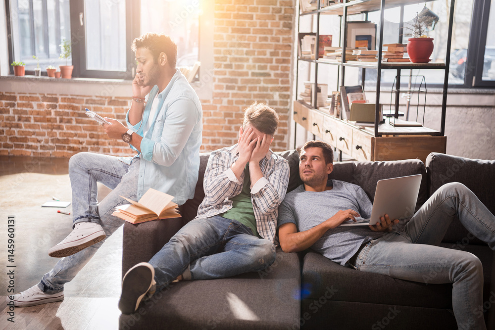 Obraz premium Young professional group sitting together on sofa with laptop and discussing