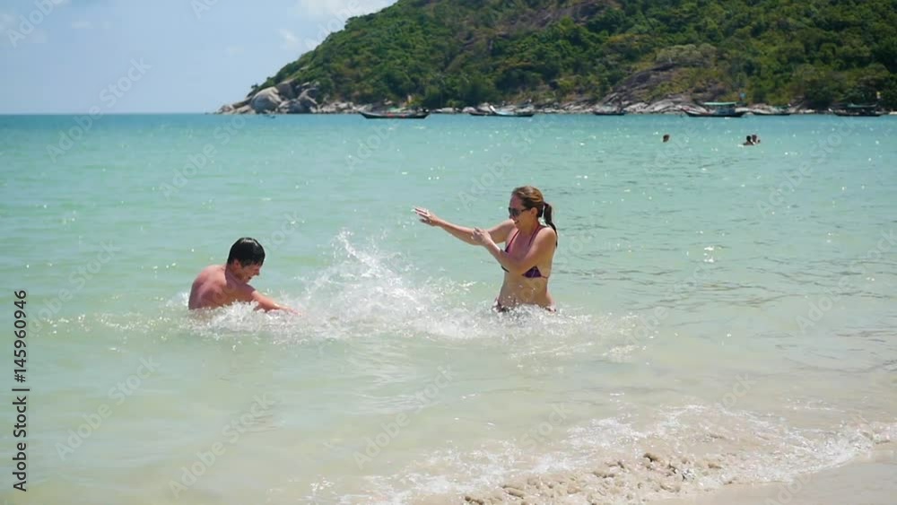 Happy guy and girl play makes splashes in the sea Happy guy and girl play makes splashes in the sea
