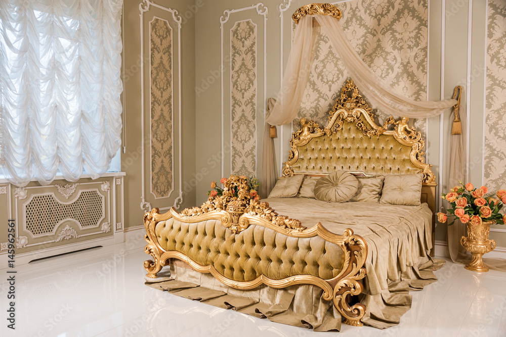 Luxury bedroom in light colors with golden furniture details. Big comfortable  double royal bed in elegant classic interior Stock Photo | Adobe Stock