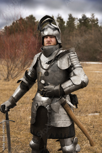 Knight in armour after battle on forest background