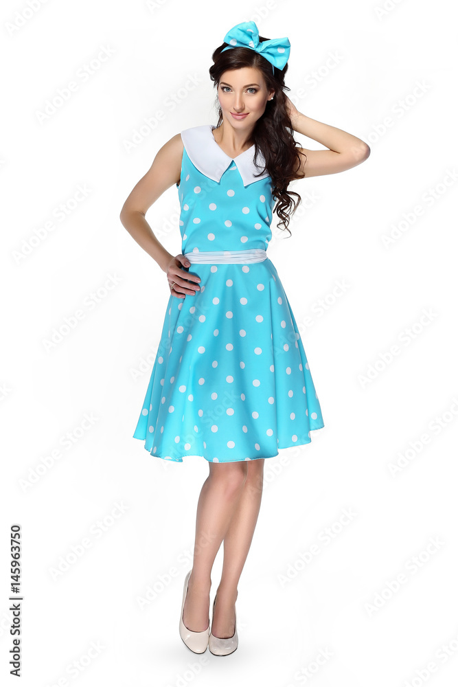 Beautiful girl in a polka-dot dress with a blue bow on a white background Beautiful girl in a polka-dot dress with a blue bow on a white background