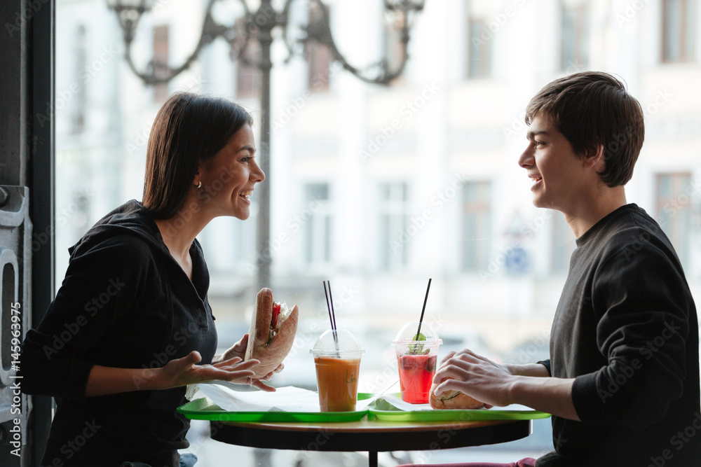 Smiling young man sitting in cafe with sister drinking juice Smiling young man sitting in cafe with sister drinking juice