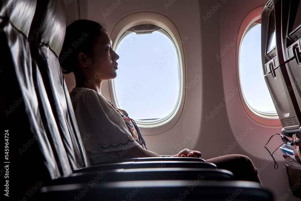 Fototapeta premium Woman sitting in a flying aircraft and watching the monitor. Passengers relax on the plane.