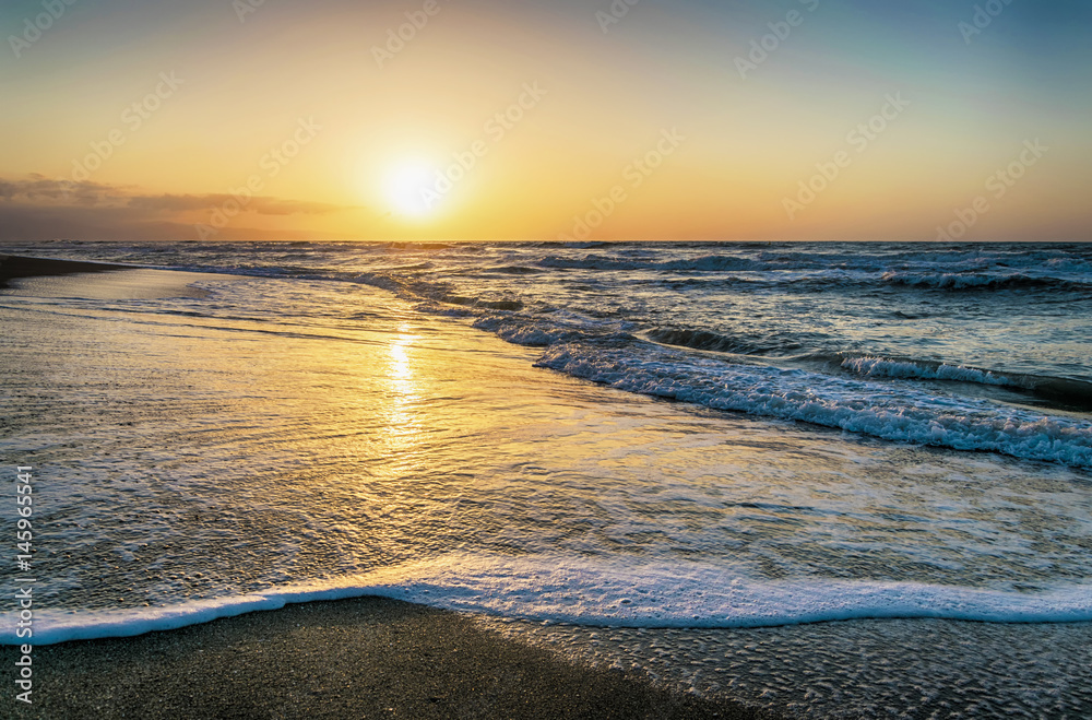 Madrugada en la playa, con bonitas tonalidades en el cielo y en el agua de la orilla del mar