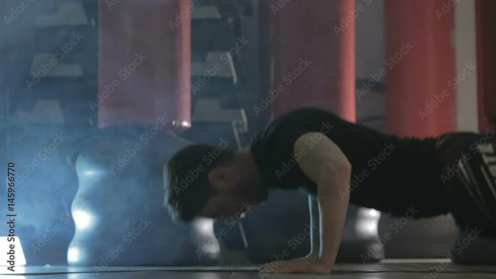Ragazzo con maglietta nera si sta allenando in palestra con i piegamenti a terra