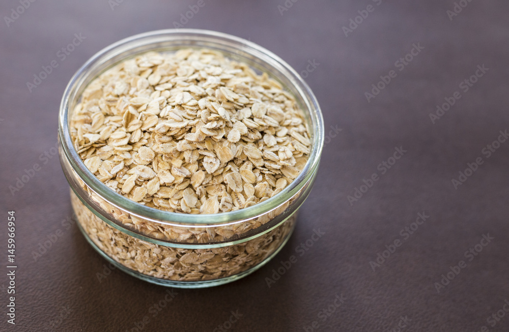 Food. Oatmeal on the table. Dry rolled oat flakes oatmeal in brown bowl on old wooden table. Food. Oatmeal on the table. Dry rolled oat flakes oatmeal in brown bowl on old wooden table.