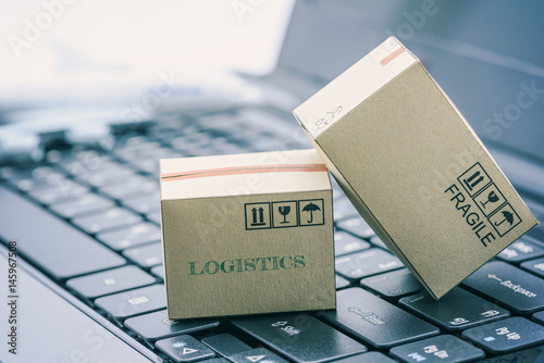 Light brown cardboard boxes on a laptop keyboard. An idea of transportation that can be done easily nowadays using an online internet at hand. Shipping / freight forwarding business concept. photo