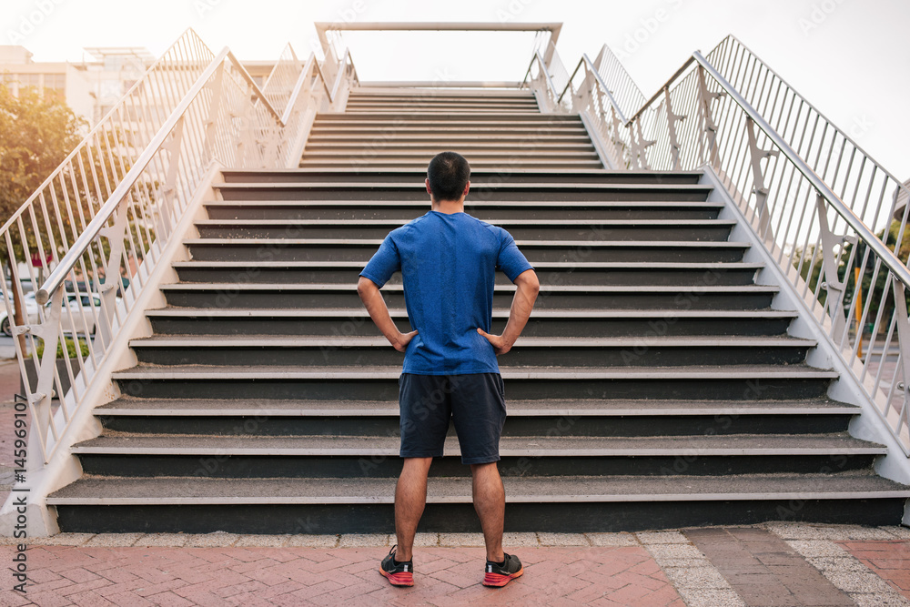 Young athletic man preparing to run up steep stairs