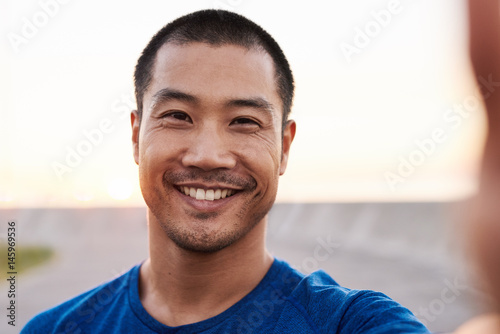 Athletic Asian man taking a selfie during a morning run