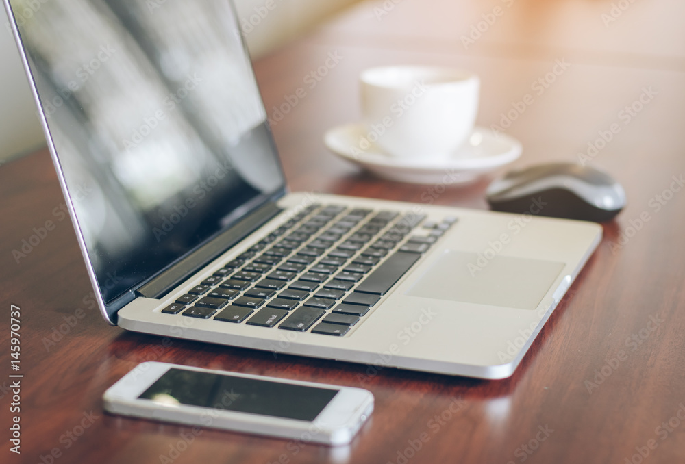 laptop, cell phone, coffee cup on wood table background in office. laptop, cell phone, coffee cup on wood table background in office.