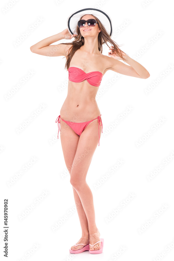 Sexy young woman posing in a pink bikini, summer hat and sunglasses, isolated on white background Sexy young woman posing in a pink bikini, summer hat and sunglasses, isolated on white background
