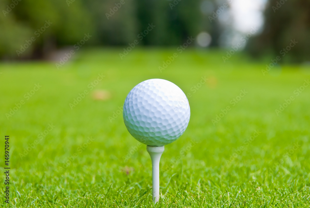 Golf ball on tee over a blurred green. Shallow depth of field. Focus on the ball. Golf ball on tee over a blurred green. Shallow depth of field. Focus on the ball.
