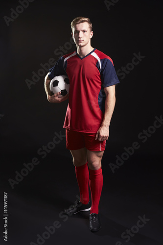 Fototapeta Naklejka Na Ścianę i Meble -  Portrait Of Professional Soccer Player With Ball In Studio