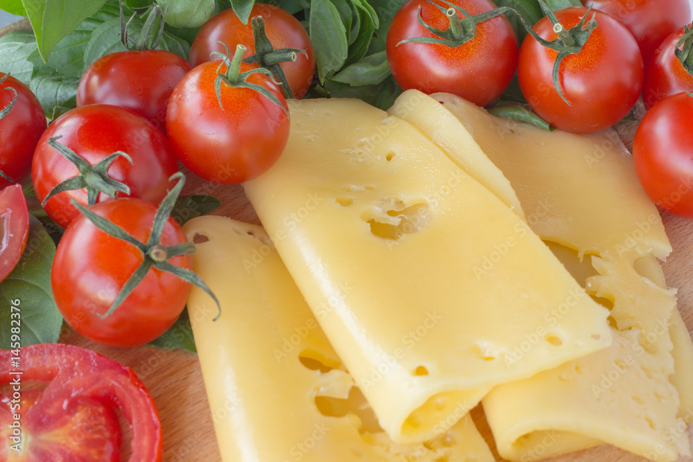 Sliced cheese, tomato and basil close up