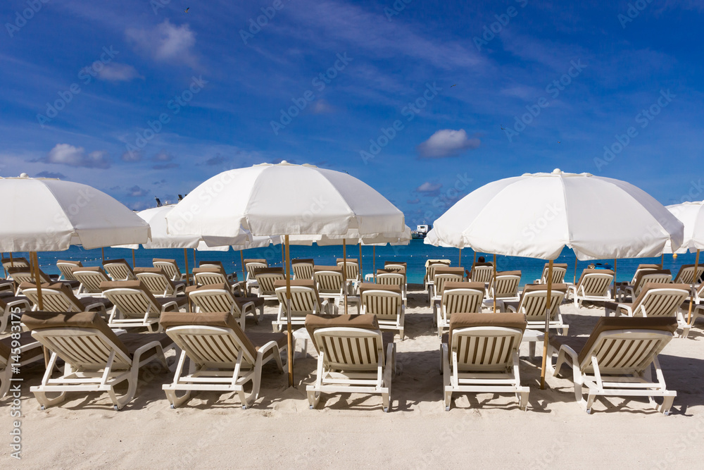  beach chairs and  white umbrellas on caribbean coast