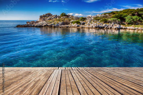Beautiful beach and old wooden pier with crystal clear sea. Berth to the shore. Summer concept. Island on the background