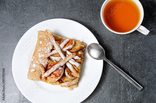 Apple pie with a cup of tea on dark stone background. Apple Pie Apples Cup of tea Piece of cake. Delicious dessert photo