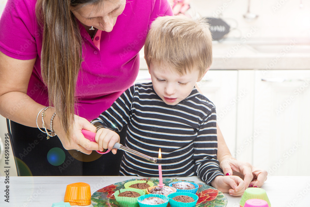 Fototapeta premium bambino e mamma che accendono la candelina di compleanno su dei muffin 