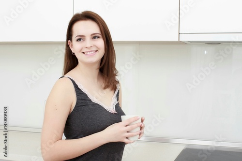 young woman With black hairdrinking coffee in the kitchen