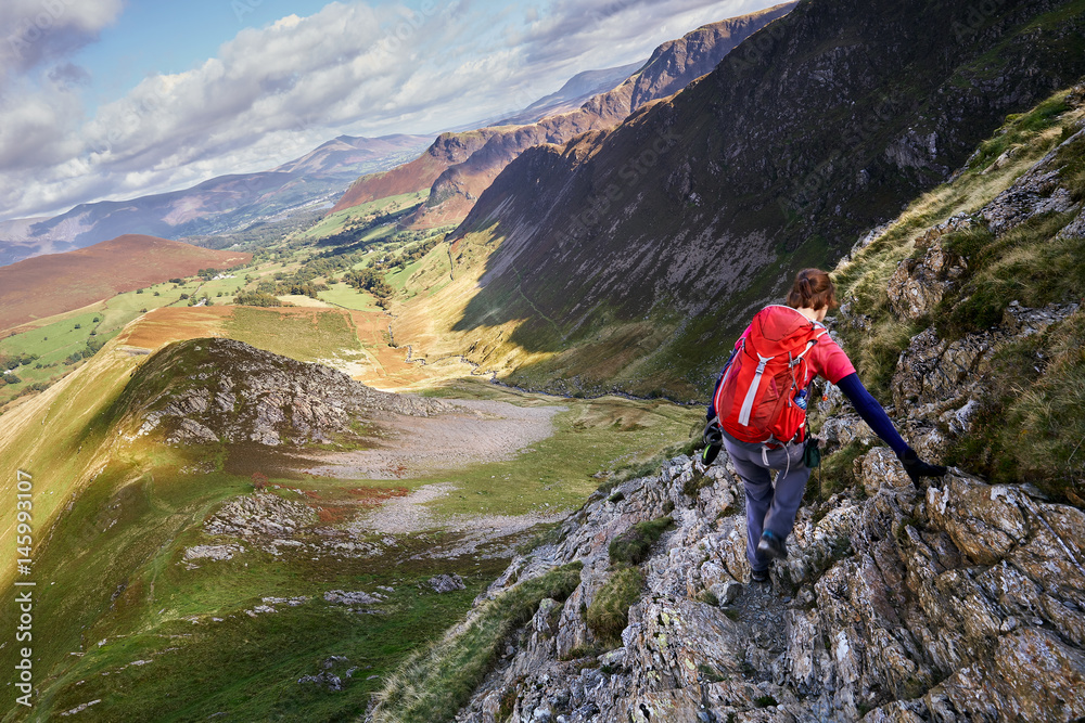 A hiker scrambling down towards High Snab Bank from the summit of Robinson in the Lake District, England, UK.