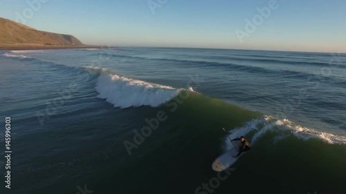 Standup paddle board surfing (SUP) a wave, aerial view New Zealand