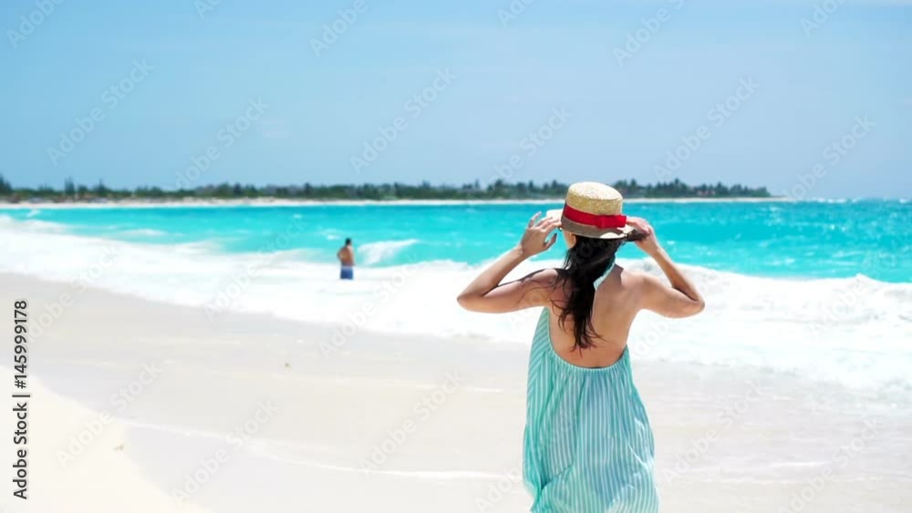 Beautiful young woman on summer holidays on white beach.Happy girl walking in summer dress in slow motion Beautiful young woman on summer holidays on white beach.Happy girl walking in summer dress in slow motion