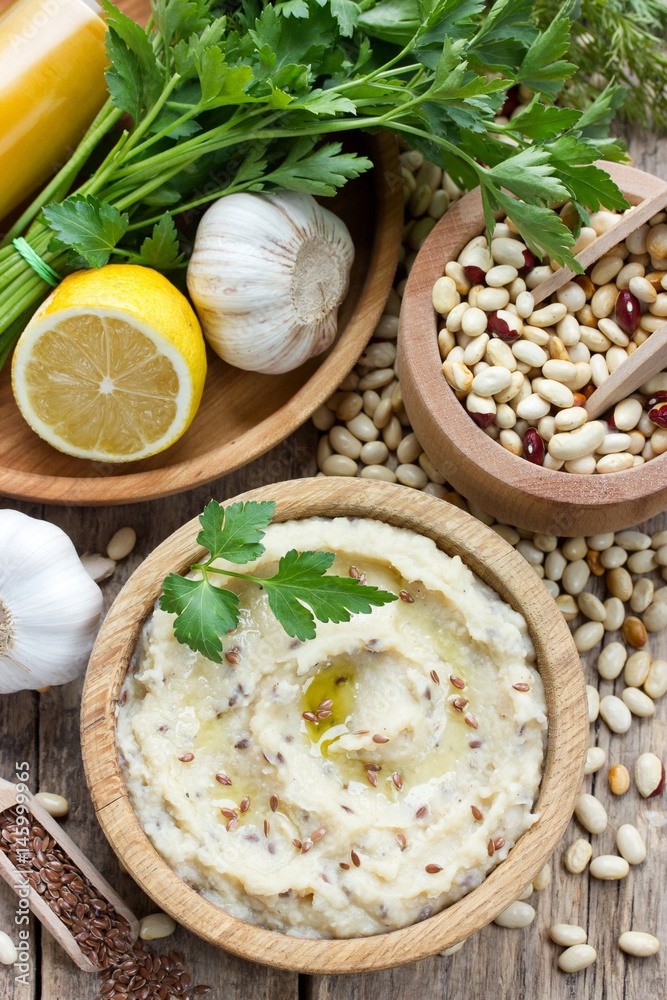 White beans hummus with lemon, garlic and flax on a wooden background