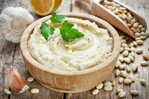 White beans hummus with lemon, garlic and flax in wooden bowl