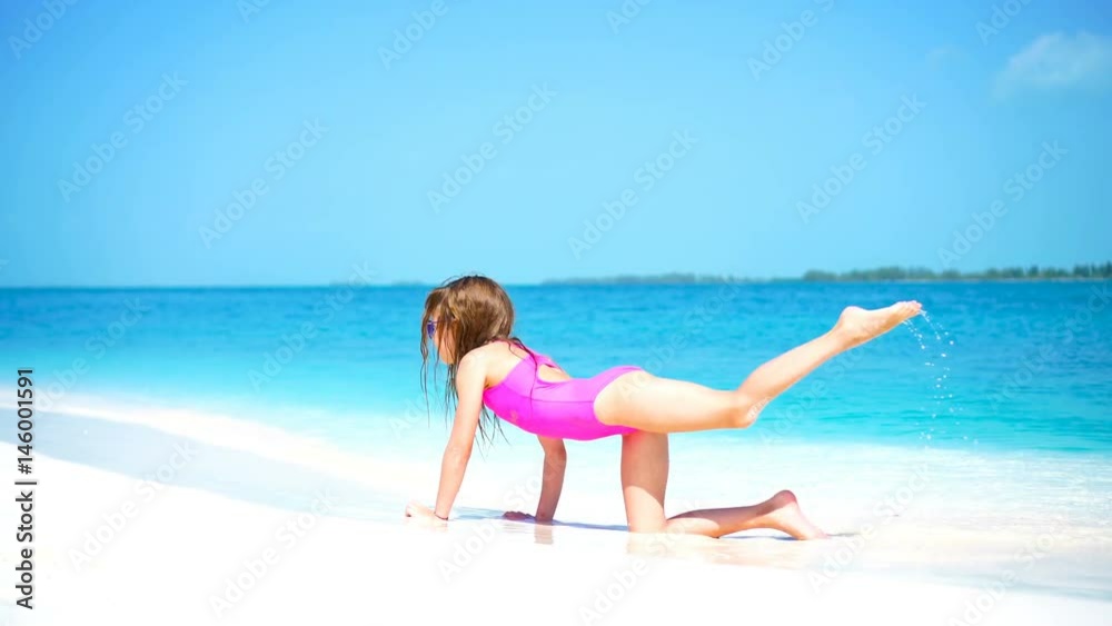 Little girl at beach having a lot of fun in shallow water on the beach Little girl at beach having a lot of fun in shallow water on the beach