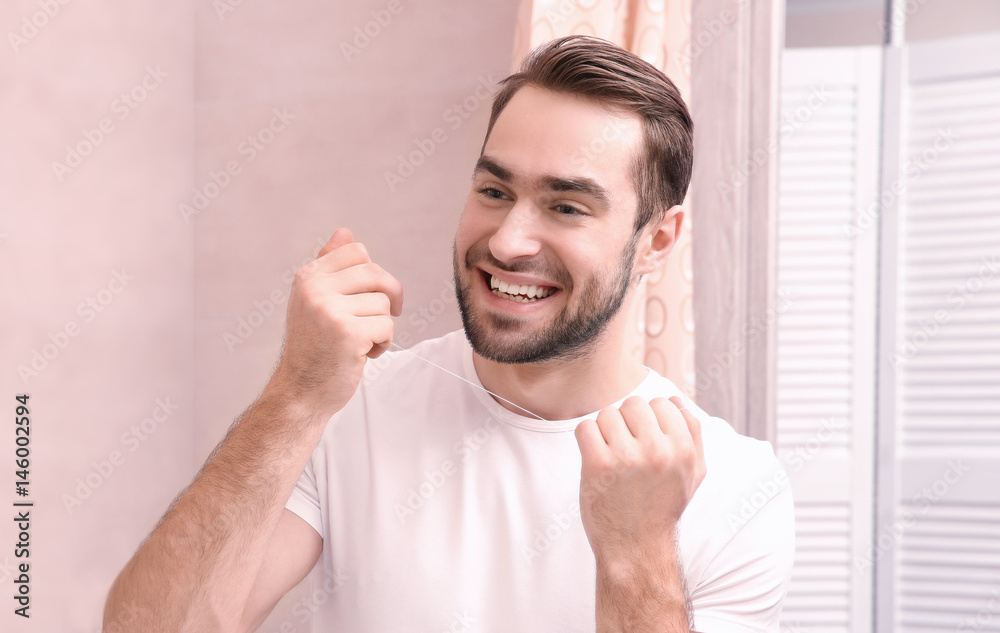 Handsome man brushing teeth in bathroom