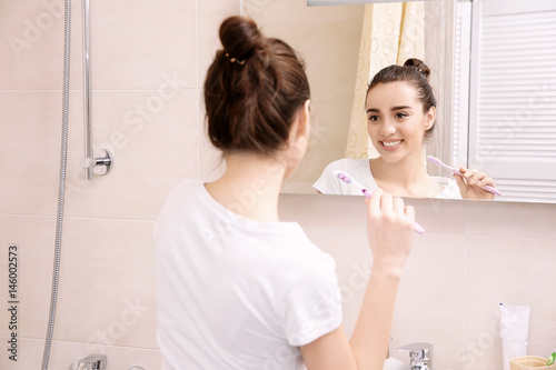 Beautiful woman brushing teeth in bathroom