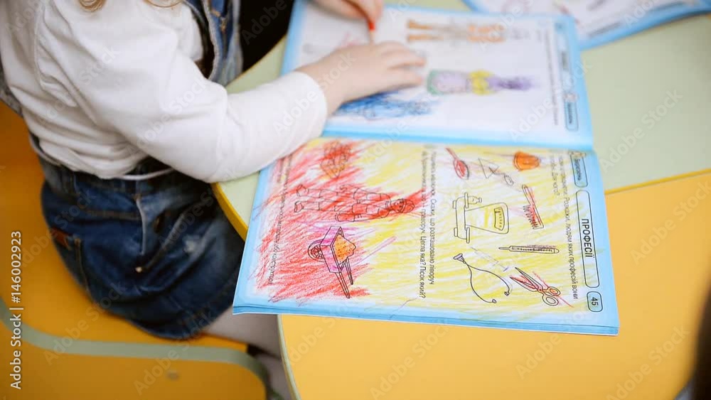The child draws with pencils. Little children sit at the table in the kindergarten and draw with pencils. The child draws with pencils. Little children sit at the table in the kindergarten and draw with pencils.
