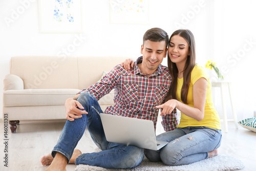 Happy young couple with lap...