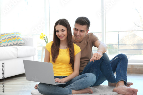 Happy young couple with lap...